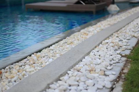 Swimming pool drainage system grating covered with round white river stone pe Stock Photos