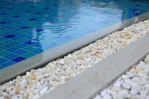 Swimming pool drainage system grating covered with round white river stone pe Stock Photos
