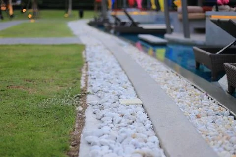 Swimming pool drainage system grating covered with round white river stone pe Stock Photos