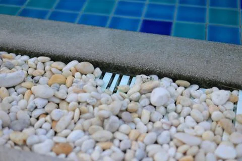 Swimming pool drainage system grating covered with round white river stone pe Stock Photos