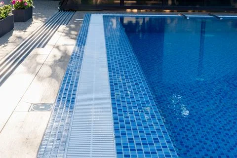 Swimming pool edge featuring a pristine blue mosaic tile pattern, an overflow Stockfoto's