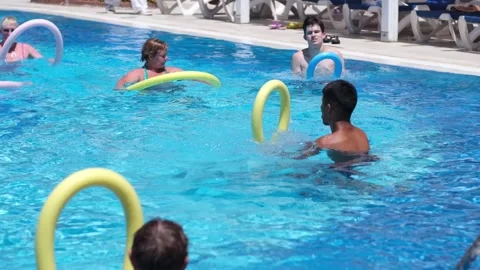 Swimming Pool Exercise Class Featuring Participants With Foam Noodles on a Sunny Stock Footage 312600106