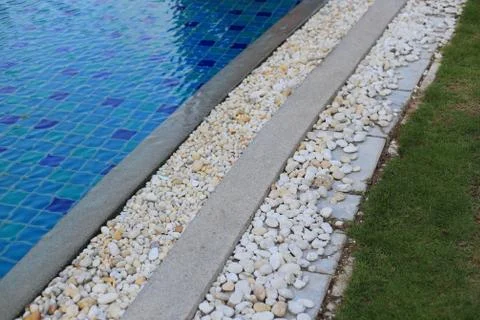 Swimming pool grating covered with round white river pebble. drainage system Stock Photos