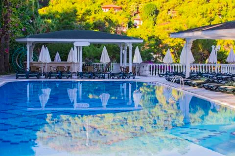Swimming pool at hotel with bar. Empty hotel, palm trees, umbrellas. Stock Photos