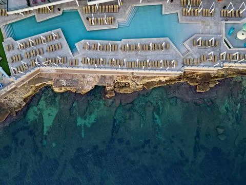 Swimming pool of irregular shape on the rocky beach Malta aerial Stock Photos
