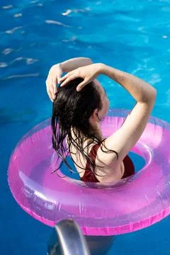Swimming in a pool with a pink float during a sunny day while enjoying the .. Fotos Stock