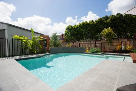 Swimming pool surrounded by trees and a garden Stock Photos