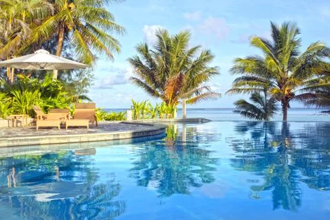 Swimming pool in tropical resort at sunset Stock Photos