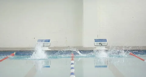 Swimming in pool, two swimmers diving into water from starting blocks, copy Stock Footage 299234361