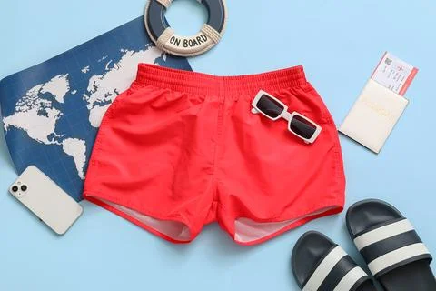 Swimming trunks with map and beach accessories on blue background Stock Photos