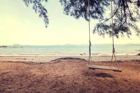 Swing on the beach under the tree with mountain back. Stock Photos