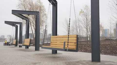 Swing benches hang from sturdy chains along park path Vídeo Stock 306458962