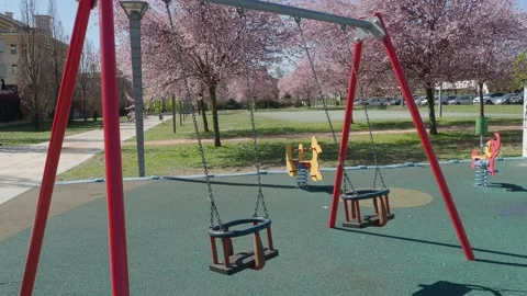 Swing close-up and flowering trees background at public park closed for lockdown Stock Footage 150438713