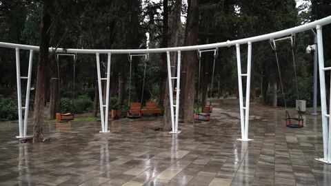 A swing in an empty park is swinging by itself without people Stock Footage 146650893