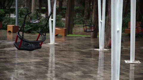 A swing in an empty park is swinging by itself without people Stock Footage 146650976
