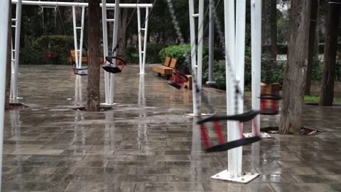 A swing in an empty park is swinging by itself without people Stock Footage 146651049