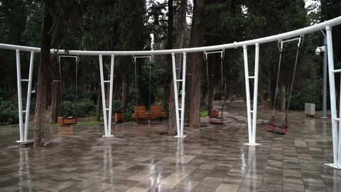 A swing in an empty park is swinging by itself without people Stock Footage 146651116