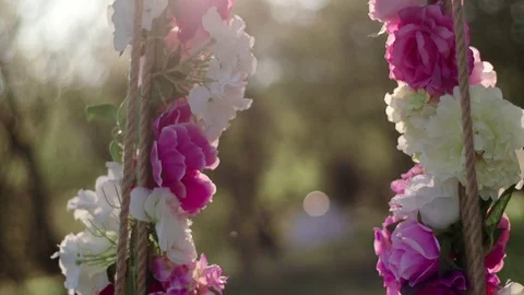 Swing in the forest decorated with flowers at sunset 動画素材 75958295