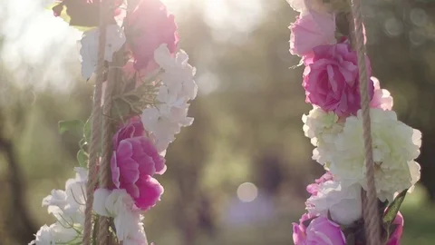 Swing in the forest decorated with flowers at sunset Video stock 75958417