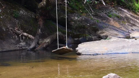 A swing over a gentle stream Stock Footage 128151401