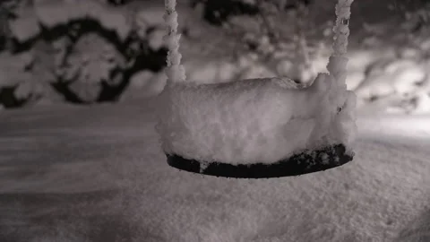 Swing at playground covered in snow during nighttime Stock Footage 231490969