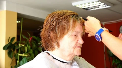 Swing professional scissors when shearing a bangs to an elderly woman Stock Footage 83569940