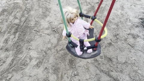A swing with red and green ropes is holding a doll, slow motion Video stock 332974905