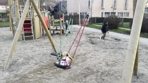 A swing with red and green ropes is holding a doll on a children's playground 스톡 동영상 333025881