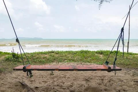 Swing on sandy beach over cloudy sky background Foto stock