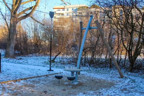 Swing set and seating area in a winter park landscape with sunlight Stock Photos