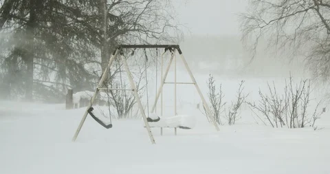 Swing Set Blowing in the Wind During a Snow Storm on a Cloudy Winter Day Видео 86625798