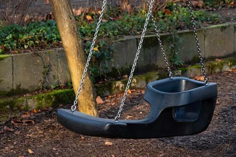 Swing set empty in a peaceful park during afternoon light Stock Photos