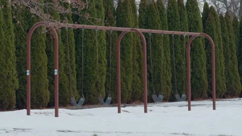 A swing set at a playground in front of trees. Stock Footage 323799580