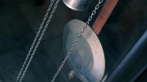 Swinging shiny metal pendulum of a large wall or floor clock with weight Stock Footage 308894748
