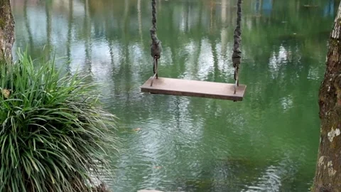 Swinging swing on the edge of the lake Stock Footage 297713325
