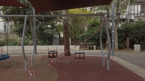 Swings in an empty playground closed for use by red and white lines tape Stock Footage 127641944