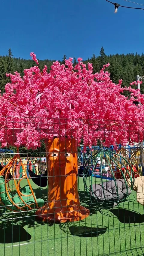 Swings Moving on Pink Artificial Tree in Playground Stock Footage 318347445