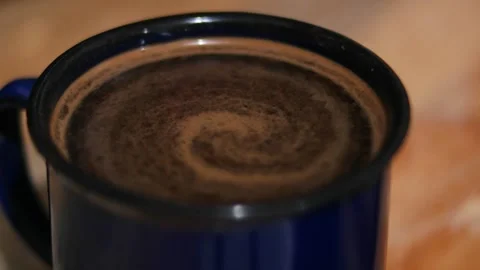 Swirling Freshly Brewed Coffee Surface in Blue Enamel Mug Video stock 339002296