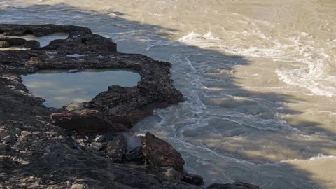 Swirling muddy river rapid flowing past rocky shoreline Stock-Footage 336812211