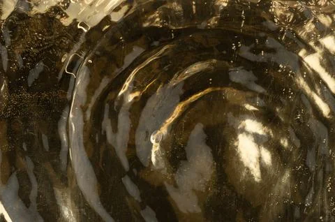 Swirling patterns in reflective golden liquid on a flat surface Stock Photos