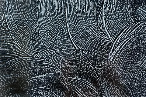 Swirling soap sud foam pattern on window with dark background. Stock Photos