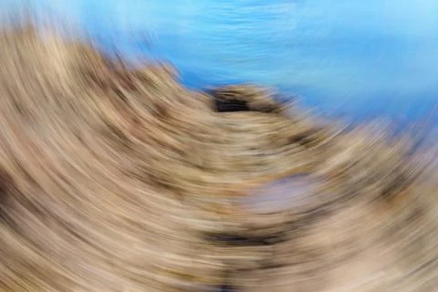 Swirling, turning movement like pattern on beach with blue of sea and brown.. Stockfoto's