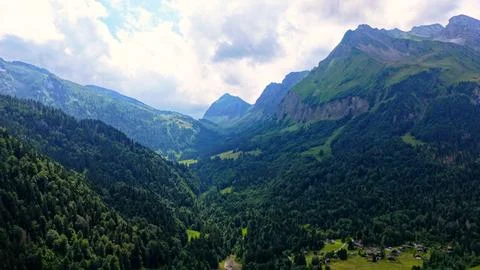 Swiss Alpine Valley with Dense Forest and Dramatic Mountain Peaks Stock Photos