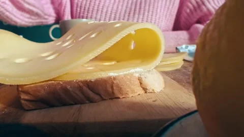Swiss Cheese Slice Being Folded over Fresh Bread at a Breakfast Table 库存影片 331099059