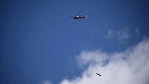 Swiss chopper carrying construction materials cargo against the blue sky Stock Footage