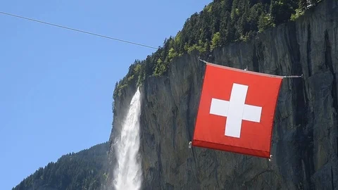 Swiss flag in front of the Staubbach Falls in Lauterbrunnen Video stock 119583180