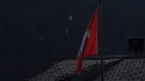 Swiss flag waving on a rooftop in the alps 스톡 동영상 307013874