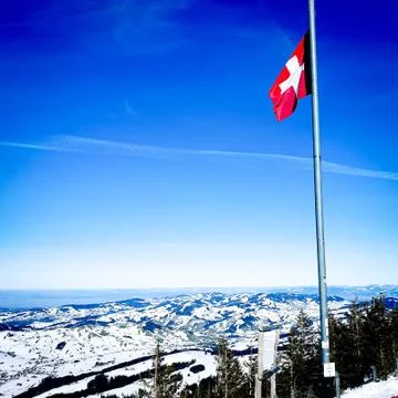 Swiss flag waving in a snowy landscape on top of a mountain Stock Photos