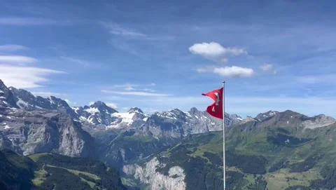Swiss Flag Waving in Wind Against Snow-Capped Alpine Mountains Vidéo 339765027