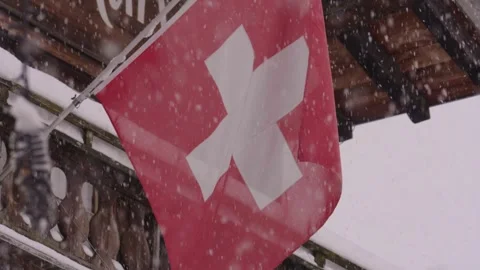 Swiss flag waving in the wind during a heavy snowfall Stockbeeldmateriaal 340836801